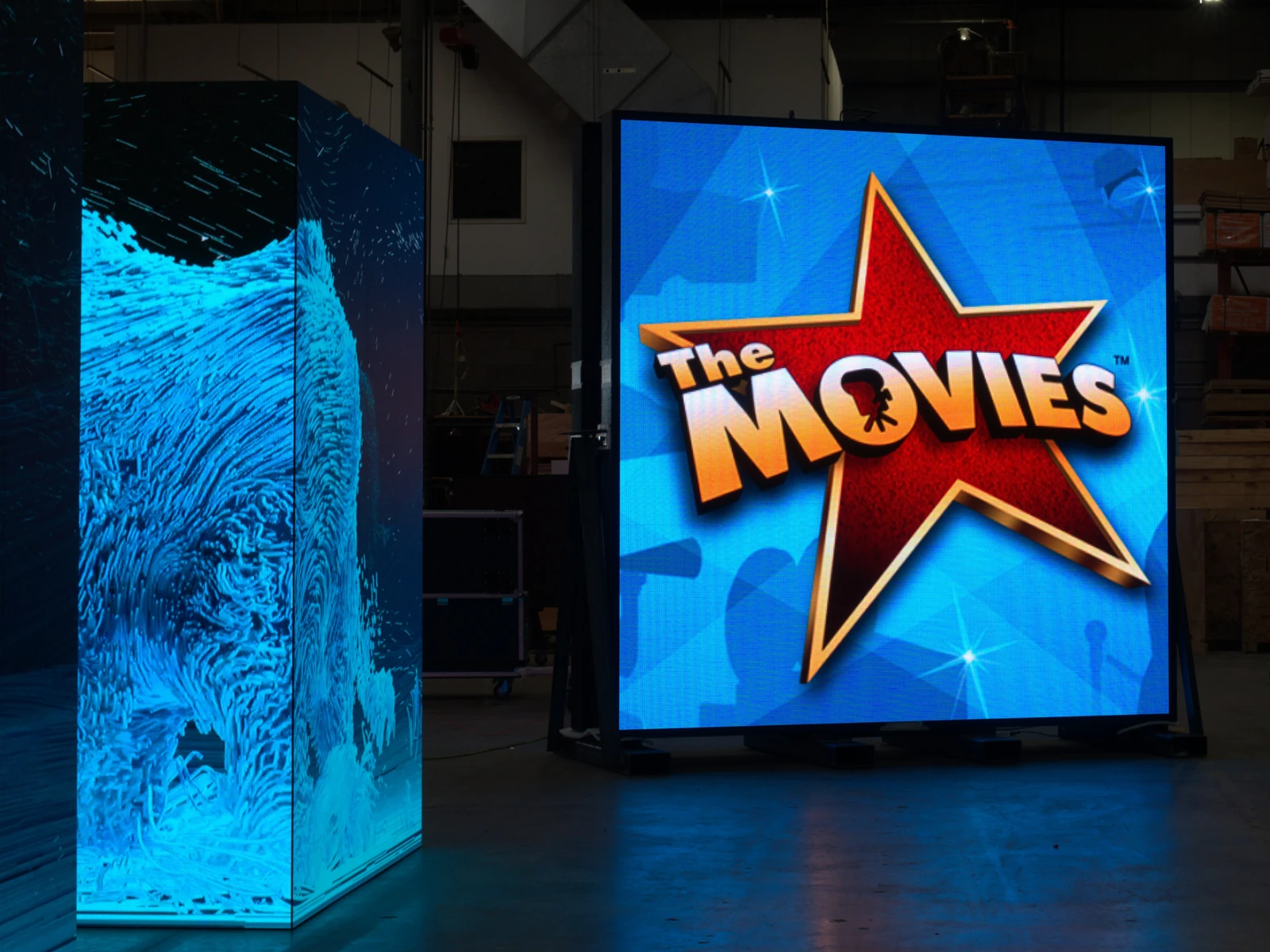 Full color LED display showing The Movies beside a blue LED display in a warehouse